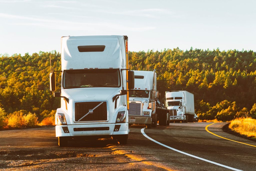 white-volvo-semi-truck-on-side-of-road-2199293 Three semi trucks driving on a highway through a forested landscape in Arizona.